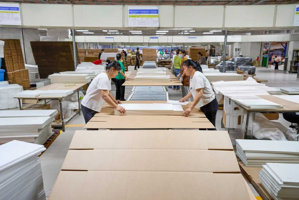 Workers packing MDF panel furniture on production line