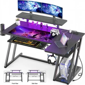 All-black L-shaped gaming desk with carbon fiber texture surface, built-in LED lighting, and keyboard tray